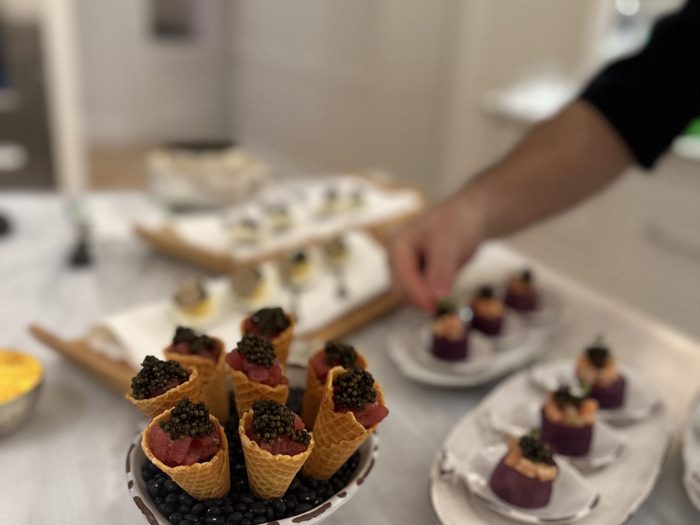 Caviar-topped cones and canap&eacute;s being plated by hand on boards and small plates for a reception