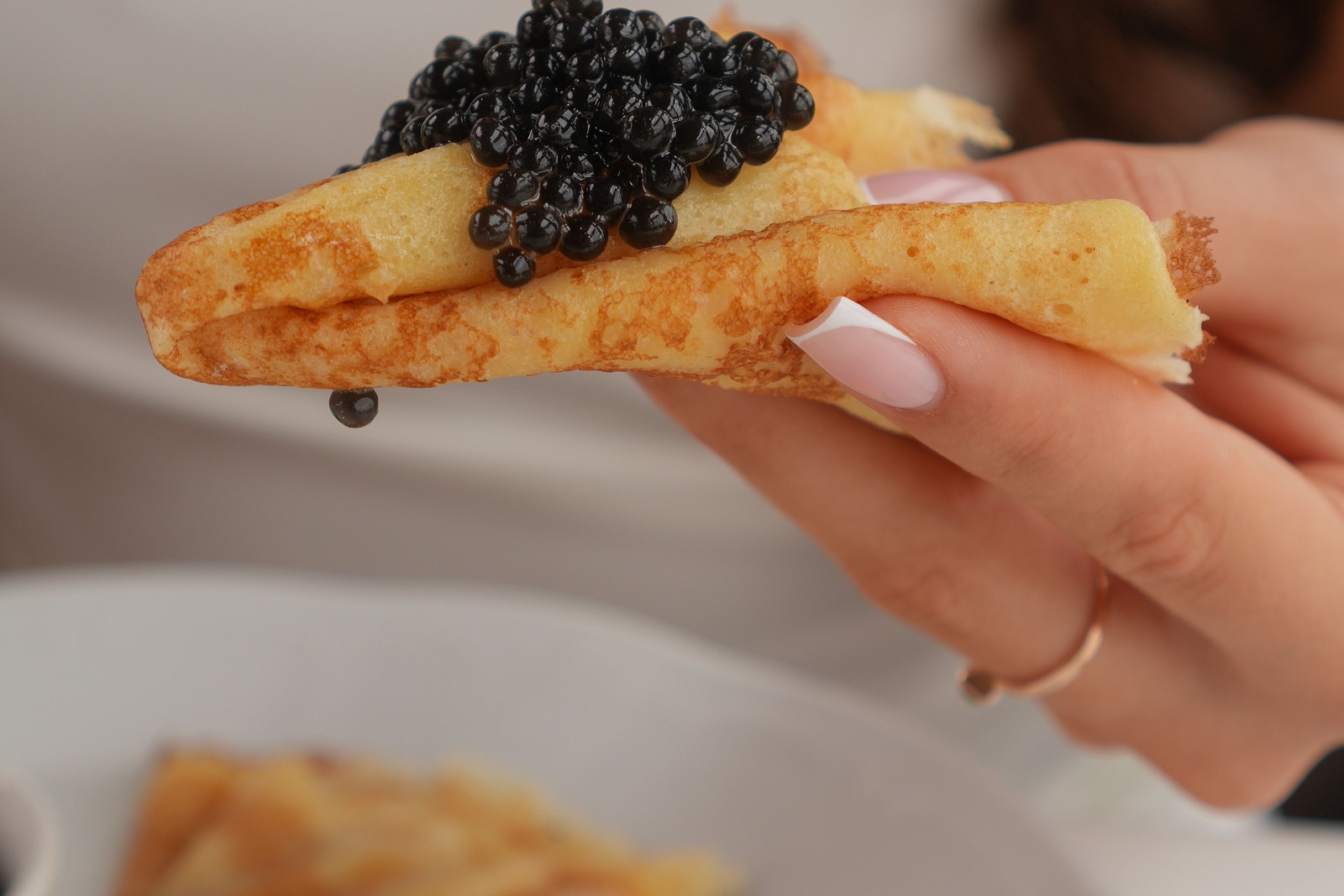 A folded crepe topped with caviar, held in the hand