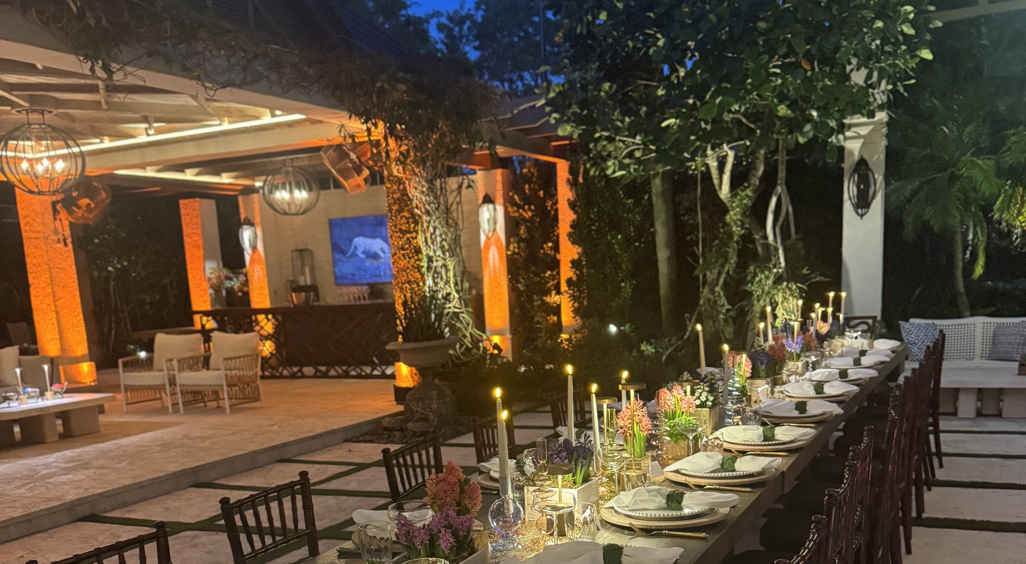 A long candlelit dinner table in a garden pavilion at a Miami home
