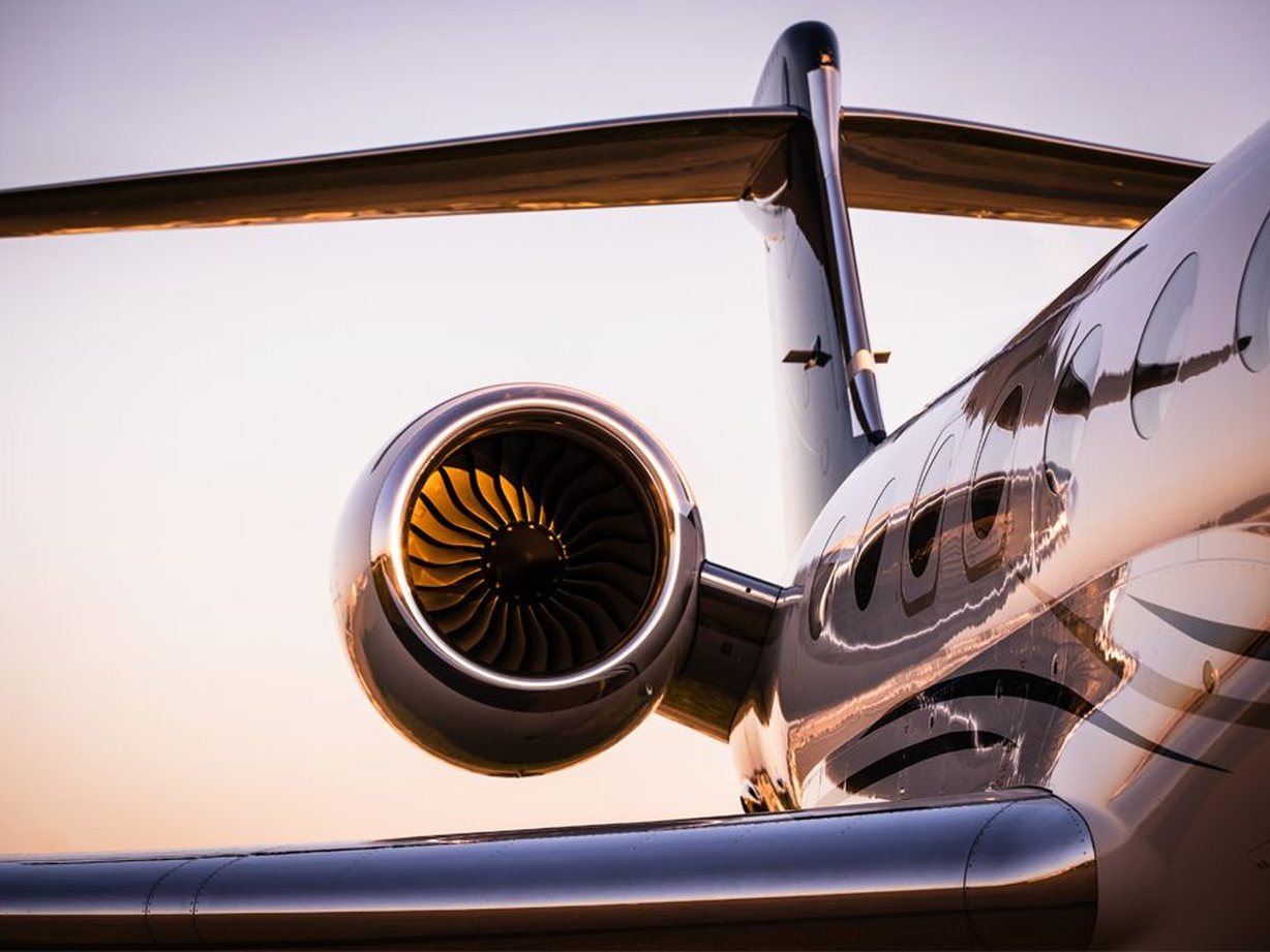 Private jet engine and wing at sunset