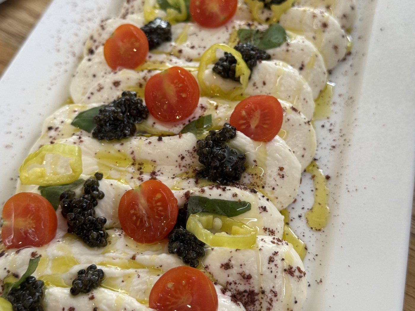 A tray of burrata with cherry tomatoes, herbs and olive oil, portioned by Chef Tasos Luxury Dining, Miami